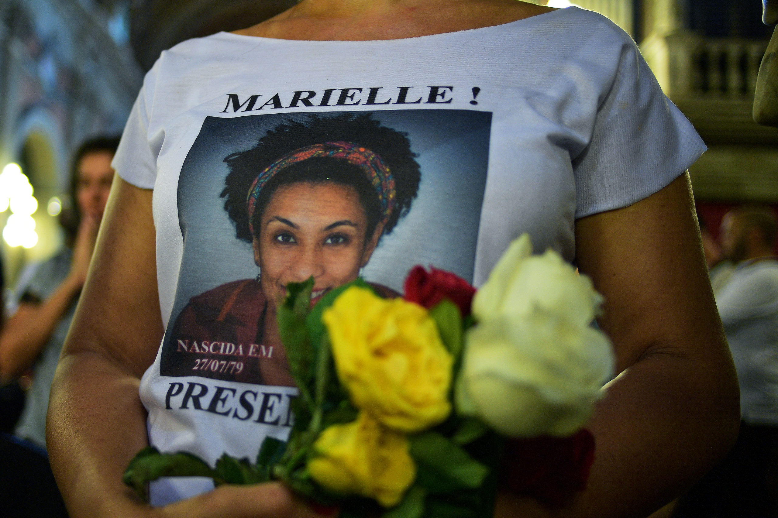 A woman wears a t-shirt bearing the portrait of slain Brazilian councilwoman Marielle Franco, during a mass celebration on the first anniversary of her death in Rio de Janeiro, Brazil on March 14, 2019. - Franco was a black gay rights activist who was an outspoken critic of police brutality and defender of the poor. A year after her murder shocked Brazil, two police officers were arrested in the case, but the motivation of the crime remains unknown. (Photo by CARL DE SOUZA / AFP)