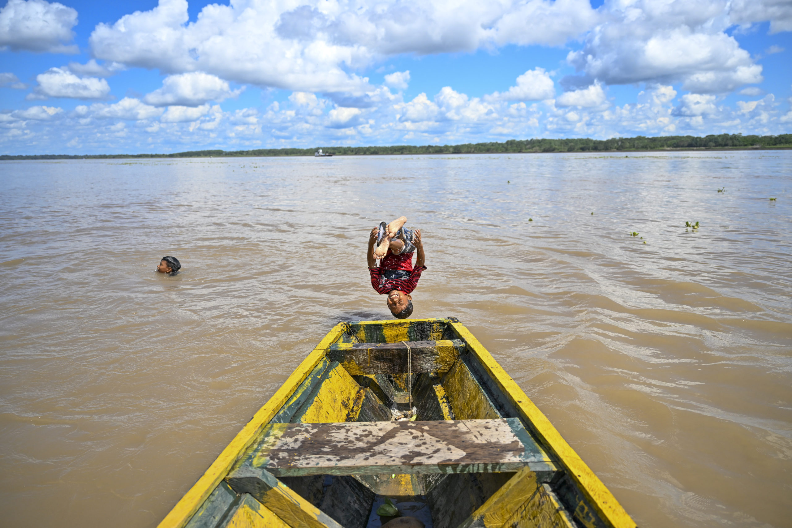 Criança do povo indígena Bora pula de um barco no rio Amazonas em Tabatinga, Brasil, na fronteira com a Colômbia e o Peru, em 9 de julho de 2023. (Foto de Juan BARRETO / AFP)