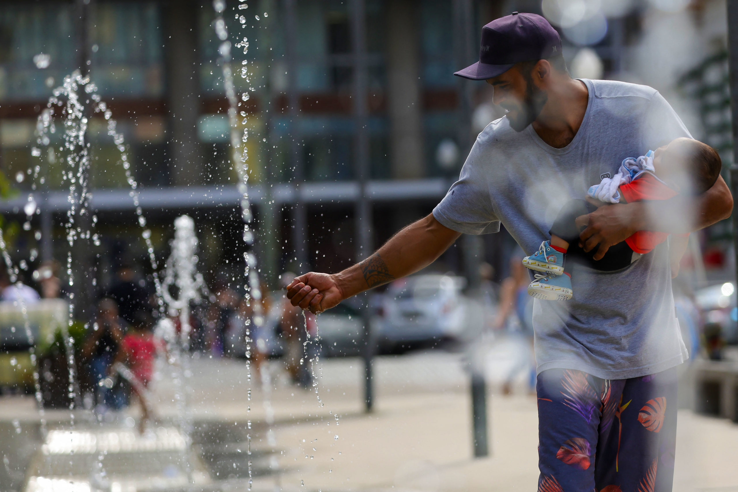 A man refreshes himself on a fountain in downtown Porto Alegre, Brazil on December 15, 2023. - A heatwave has hit Rio Grande do Sul, and the temperature could reach 43 ºC. This wave, which began on December 14, is expected to last until at least Sunday, close to the arrival of summer, which is on December 22. The National Institute of Meteorology has issued an orange heatwave alert covering the entire state, which is also a warning of the health risks posed by extreme temperatures. (Photo by SILVIO AVILA / AFP)